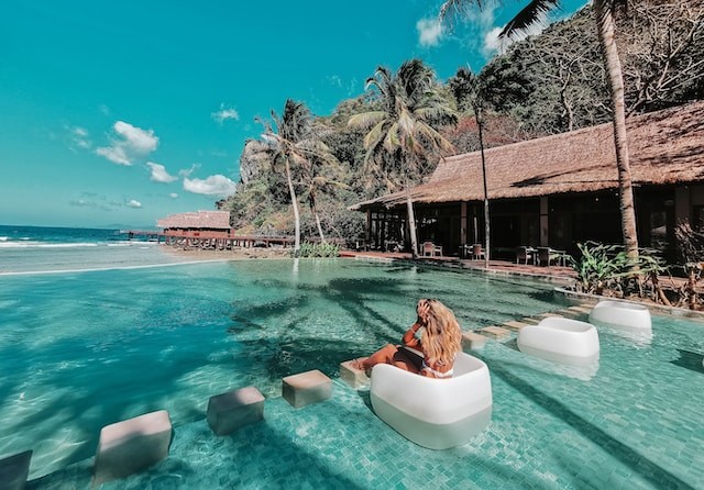 person sitting on rock in the sea in front of beautiful island